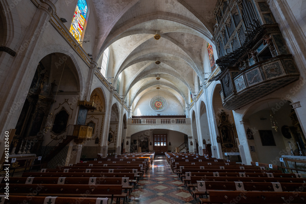 The interior of the old historic church of Felanitx on the Spanish Mediterranean island of Mallorca. At the back is the entrance and to the right and left are benches. At the top right is the organ.