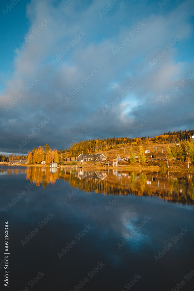Autumn sunset at Lake Syvajarvi, in Hyrynsalmi, Finland. Reflection of red-orange petals on the lake surface. Storm clouds at sunset. Autumn vibes