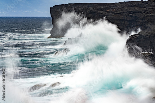 sea in tempest breaking waves on lava rock cliff photo
