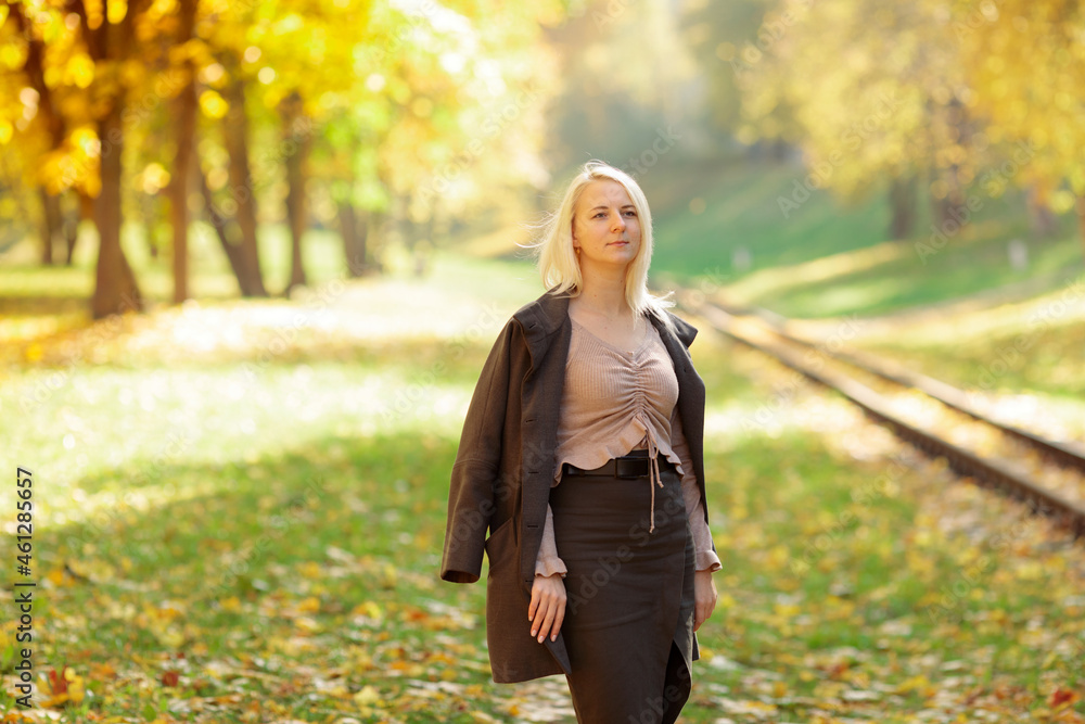 Young blonde woman in the park on a background of yellow autumn foliage Young blonde woman in the park on a background of yellow autumn foliage