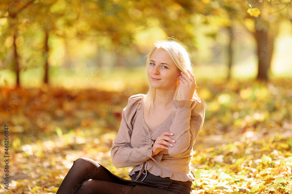 Young blonde woman in the park on a background of yellow autumn foliage Young blonde woman in the park on a background of yellow autumn foliage