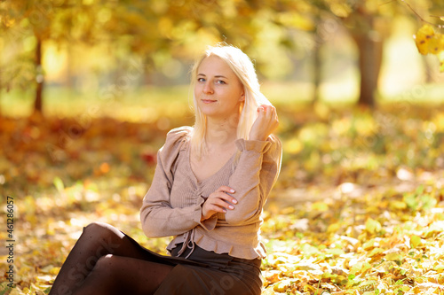 Young blonde woman in the park on a background of yellow autumn foliage
