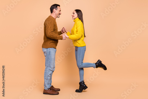 Full size profile photo of brunette couple hold arms wear autumn knitwear sweater jeans shoes isolated on beige background