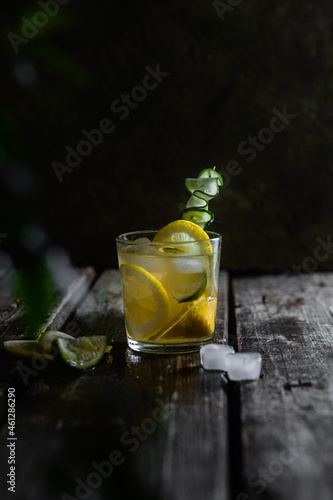 Cocktail with lemon, lime and ice in a glass on a dark background