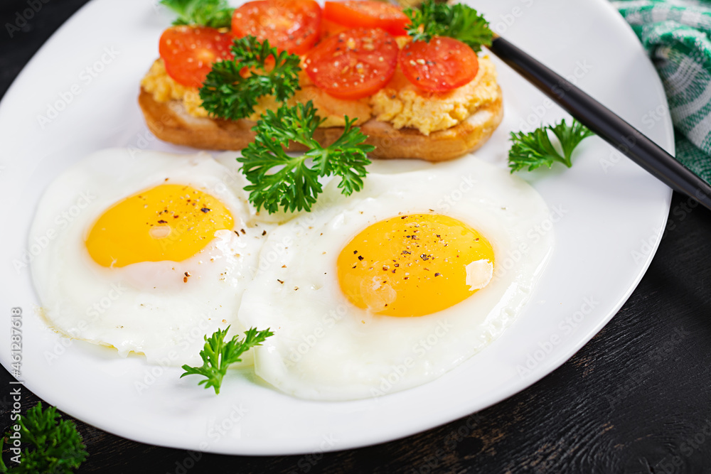 Fried eggs and a grilled chicken pate sandwich on a dark background. Fried eggs and a grilled chicken pate sandwich on a dark background.