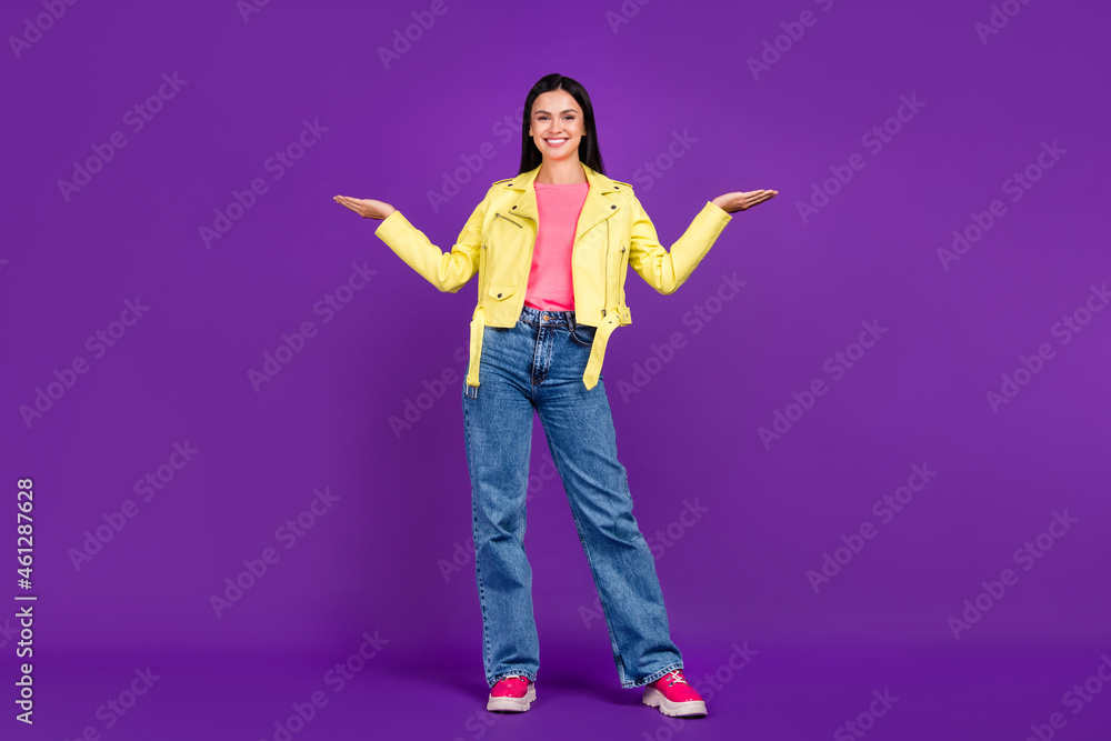 Full body photo of young cheerful girl promoter hold hands proposition vs scales measure ads isolated over violet color background Full body photo of young cheerful girl promoter hold hands proposition vs scales measure ads isolated over violet color background