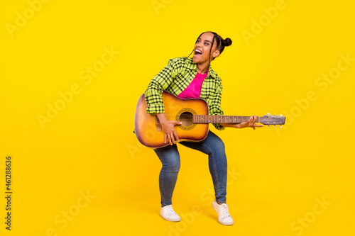 Full size photo of trendy brown haired afro american woman look empty space guitar isolated on yellow color background
