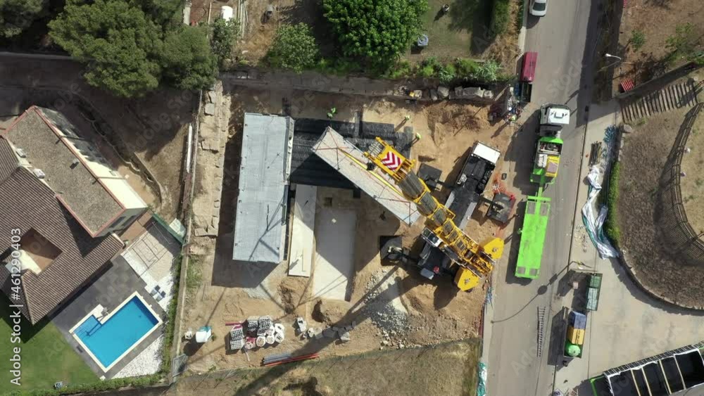 Rising Birdseye aerial view above crane lifting contemporary module property into real estate construction site Rising Birdseye aerial view above crane lifting contemporary module property into real estate construction site