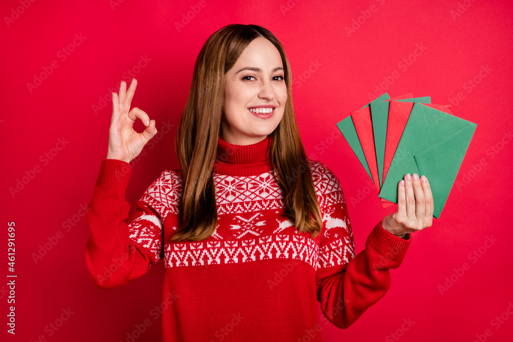 Portrait of attractive cheerful girl holding in hands letters December miracle showing ok-sign isolated over bright red color background Portrait of attractive cheerful girl holding in hands letters December miracle showing ok-sign isolated over bright red color background