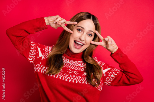 Portrait of attractive cheerful girl showing double v-sign having fun dancing isolated over vibrant red color background