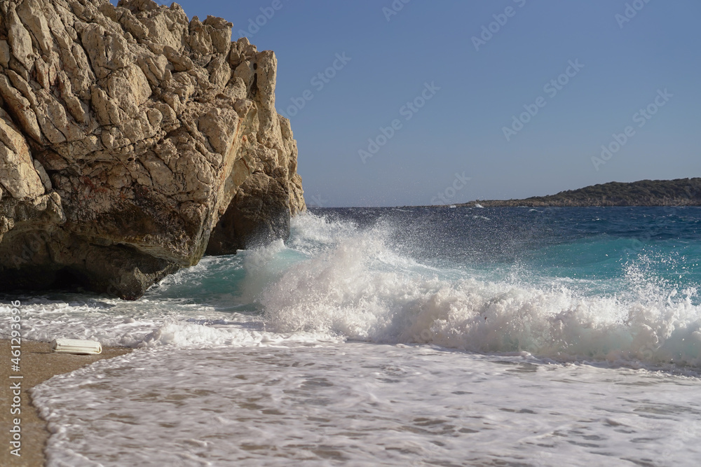Beach in Turkey with fine yellow sand and azure water, waves crashing against the rock Beach in Turkey with fine yellow sand and azure water, waves crashing against the rock