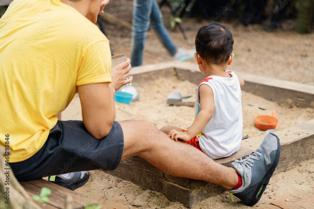 Authentic asian little boy playing sand with his father take care and feeding him by his side. Son and dad having happy nature moment time togetherness in summer. Father's day concept. Authentic asian little boy playing sand with his father take care and feeding him by his side. Son and dad having happy nature moment time togetherness in summer. Father's day concept.