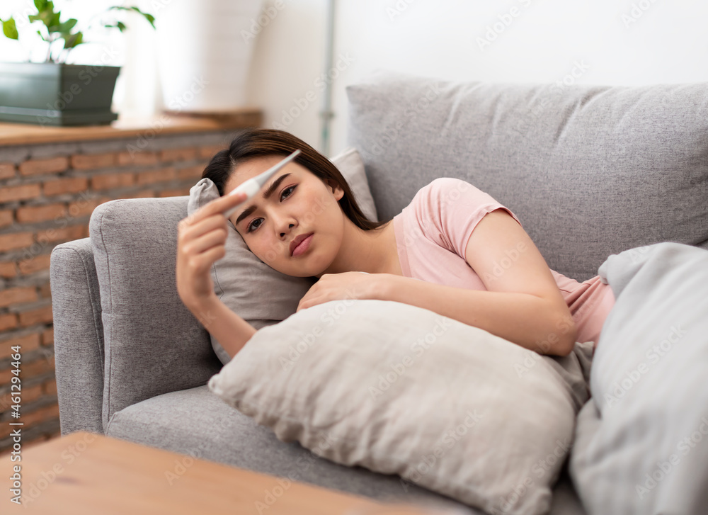 Asian young woman is sick, unwell, cold and holding a thermometer after measuring temperature. Asian young woman is sick, unwell, cold and holding a thermometer after measuring temperature.