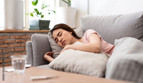 Young woman is sick, unwell, cold and sleep on the sofa. After taking medicine, Selective focus