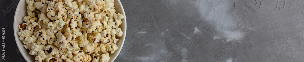 banner of Popcorn in white bowl on grey table. Top view with copyspace