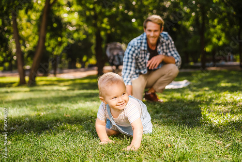 White father playing with his son while resting on grass © Drobot Dean