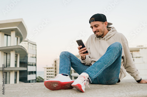 Young handsome man using phone on the street. Sitting with smartphone.