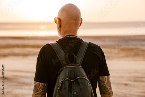 Bold senior man with backpack looking aside outdoors © Drobot Dean