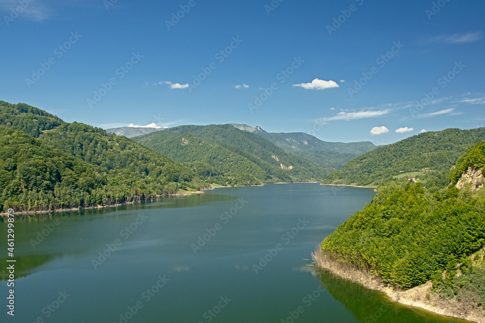 Buzau lake in between mountains with forests on a sunny day with blue sky in the Transylvanian countryside near Gura Siriului 