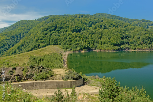 Buzau lake in between mountains with forests on a sunny day with blue sky in the Transylvanian countryside near Gura Siriului 