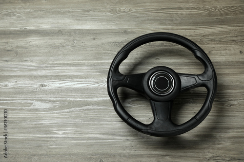 New black steering wheel on grey wooden table, top view. Space for text