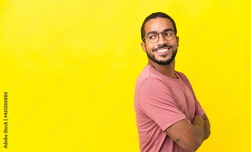 Young latin man isolated on yellow background looking to the side and smiling Young latin man isolated on yellow background looking to the side and smiling