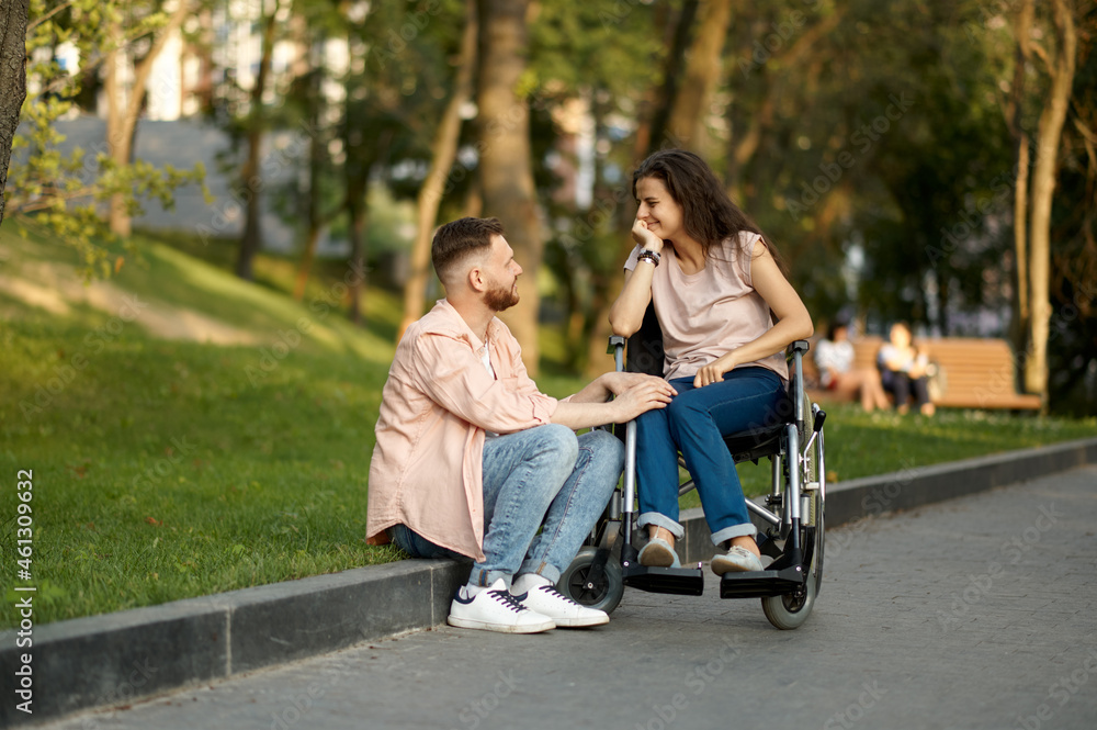 Couple with wheelchair in park, disabled woman Couple with wheelchair in park, disabled woman