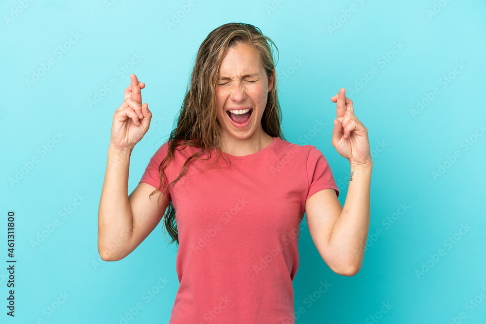 Young caucasian woman isolated on blue background with fingers crossing Young caucasian woman isolated on blue background with fingers crossing