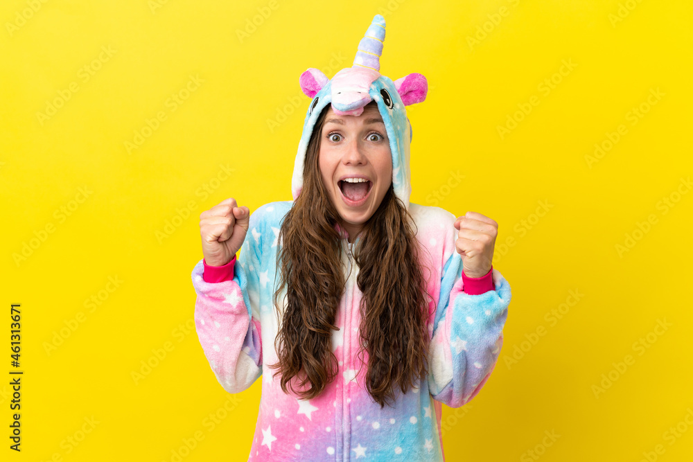 Girl with unicorn pajamas over isolated background celebrating a victory in winner position Girl with unicorn pajamas over isolated background celebrating a victory in winner position