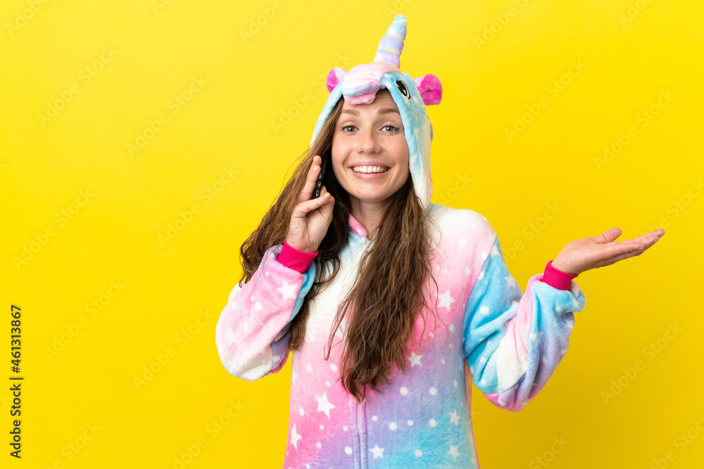 Girl with unicorn pajamas over isolated background keeping a conversation with the mobile phone with someone Girl with unicorn pajamas over isolated background keeping a conversation with the mobile phone with someone