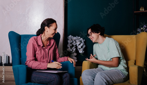 a female psychologist and a teenage patient are sitting in chairs in the office and having a conversation