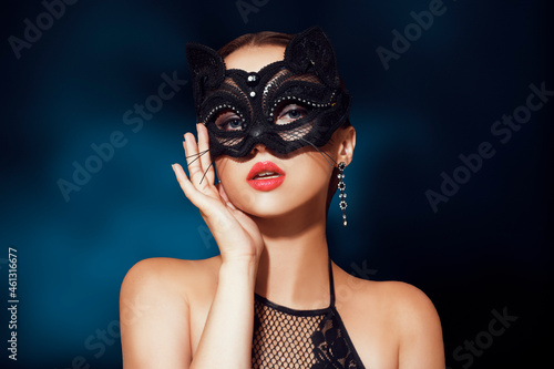 The girl in the mask. Masquerade, halloween. Girl in a cat mask. Catwoman on a beautiful background in a beautiful lace top with long earrings .