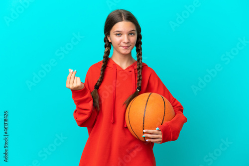 Little caucasian girl playing basketball isolated on blue background making money gesture
