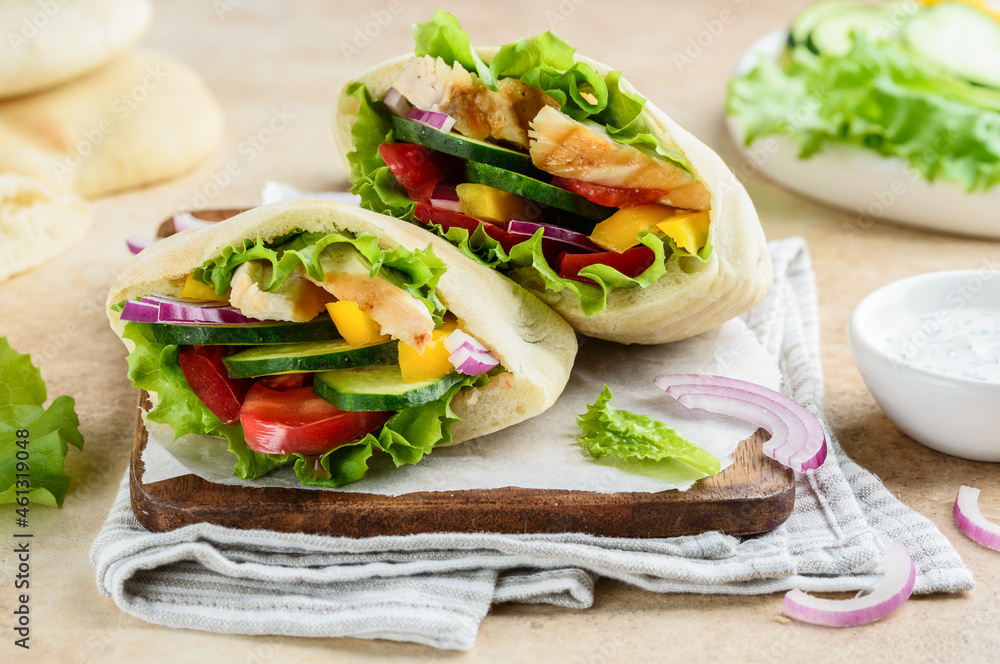 Obraz premium Pita with roasted chicken and vegetables: cucumber, tomato, pepper, red onion and yoghurt sauce. Healthy food. Selective focus