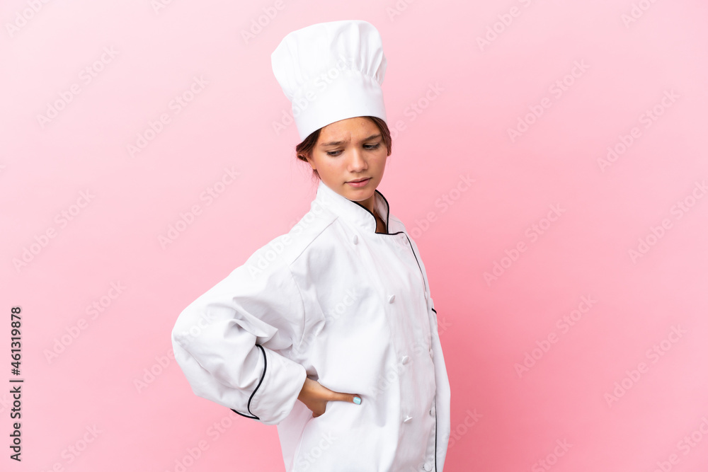 Little caucasian chef girl isolated on pink background suffering from backache for having made an effort Little caucasian chef girl isolated on pink background suffering from backache for having made an effort