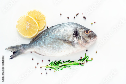 raw dorado fish with lemon and rosemary on a white plate