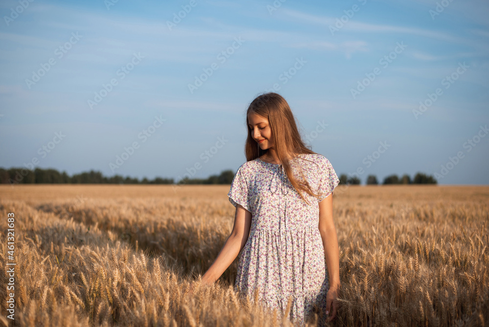 Portrait of a young girl having a walk in endless field of ripe rye. Evening calm atmosphere in the agricultural field Portrait of a young girl having a walk in endless field of ripe rye. Evening calm atmosphere in the agricultural field