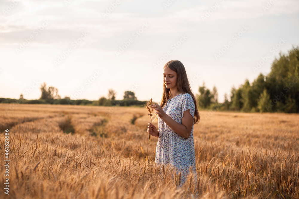 Portrait of young blond girl with some rye ears in her hands in field of rye at sunset. Lonely girl in field of rye Portrait of young blond girl with some rye ears in her hands in field of rye at sunset. Lonely girl in field of rye
