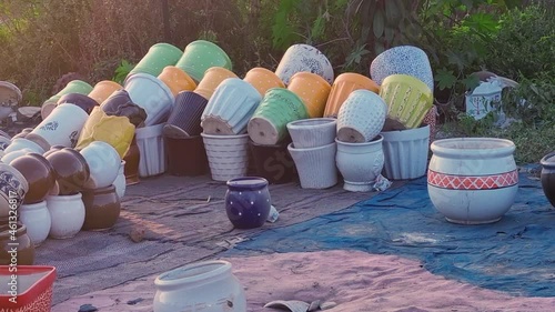 zoomed in shot in the dusk golden sunlight showing colorful ceramic clay pots pans planters vessels placed on a mat on the side of road in gurgaon banjara market photo