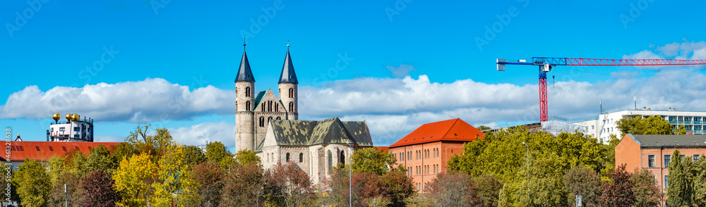 Panoramic view over Church Monastery of Our Beloved in historical downtown and park of Magdeburg at blue sky with clouds and golden Autumn colors with construction crane, Magdeburg, Germany.