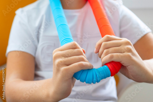 colorful antistress sensory toy fidget push pop tube in kid s hands on yellow background