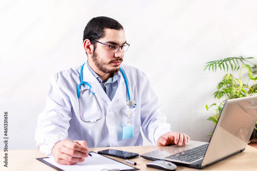 Doctor work on laptop and making notes. Doctor work on laptop and making notes.