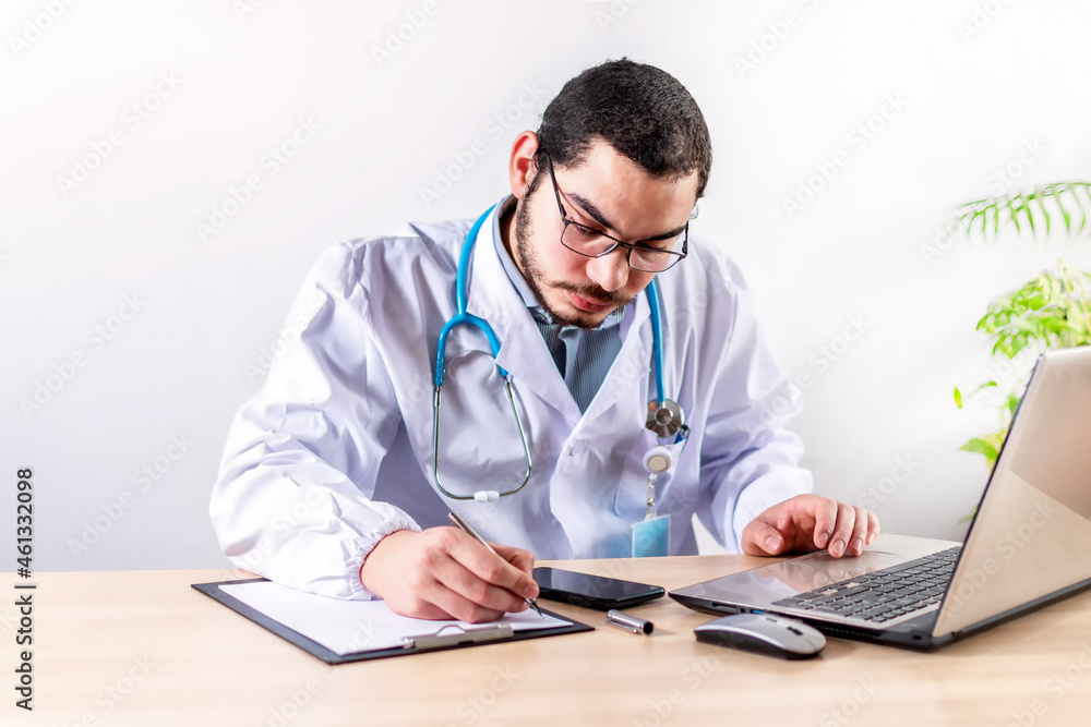 Doctor sitting alone at desk in his office doing paper work. Doctor sitting alone at desk in his office doing paper work.