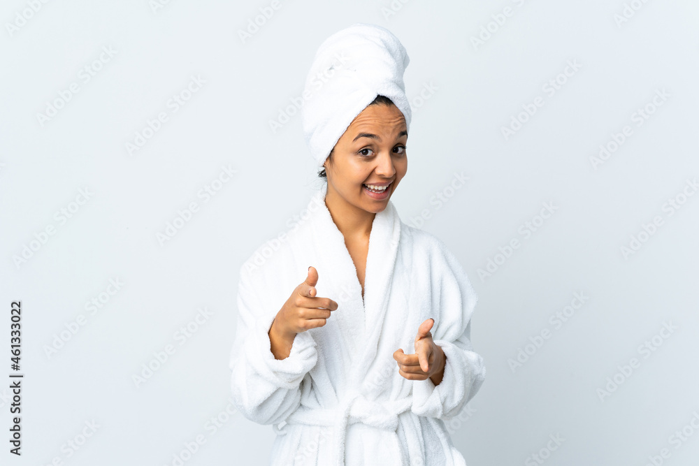 Young woman in bathrobe over isolated white background surprised and pointing front Young woman in bathrobe over isolated white background surprised and pointing front