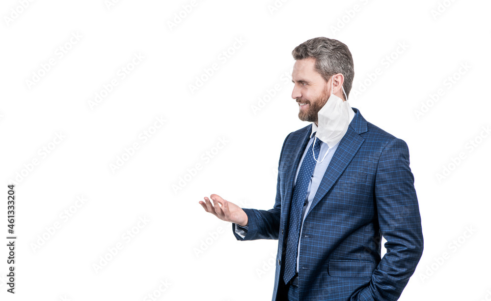 Happy professional man in suit with face mask hanging off ear stand sideway, post-covid Happy professional man in suit with face mask hanging off ear stand sideway, post-covid