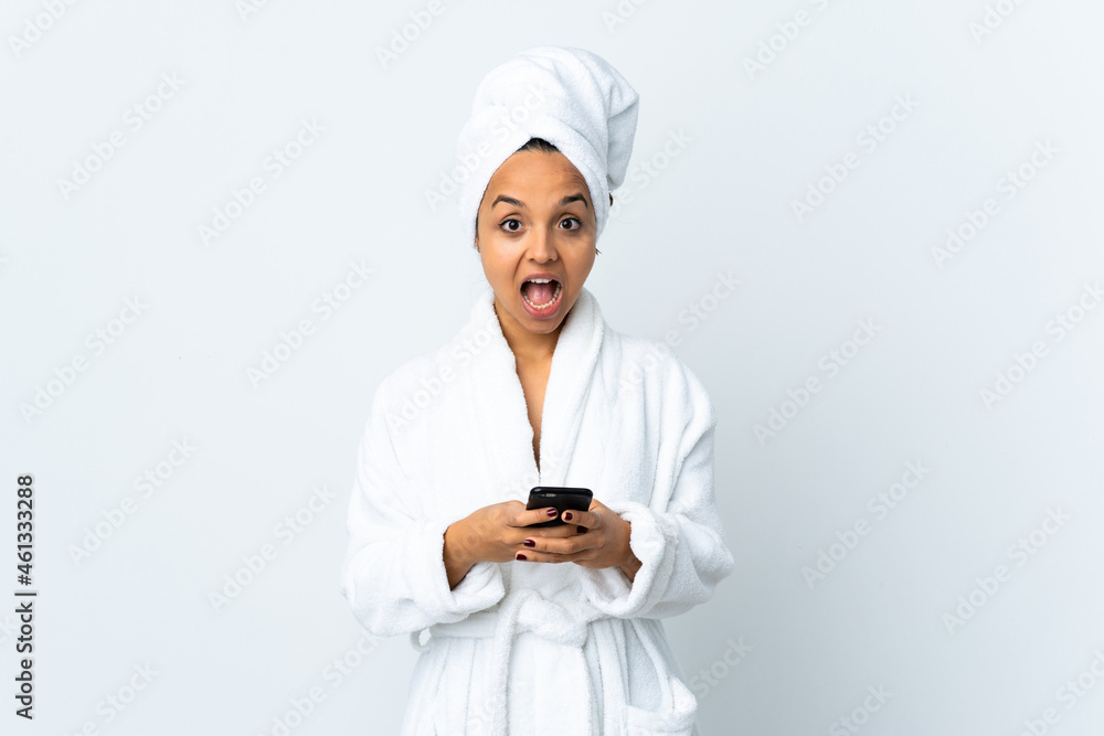 Young woman in bathrobe over isolated white background surprised and sending a message Young woman in bathrobe over isolated white background surprised and sending a message