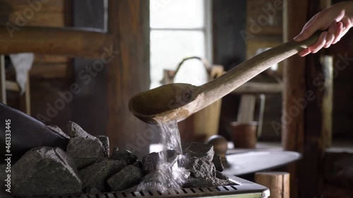 Interior of traditional Finnish sauna with wooden accessories and steam. Splashing water on hot stones. photo