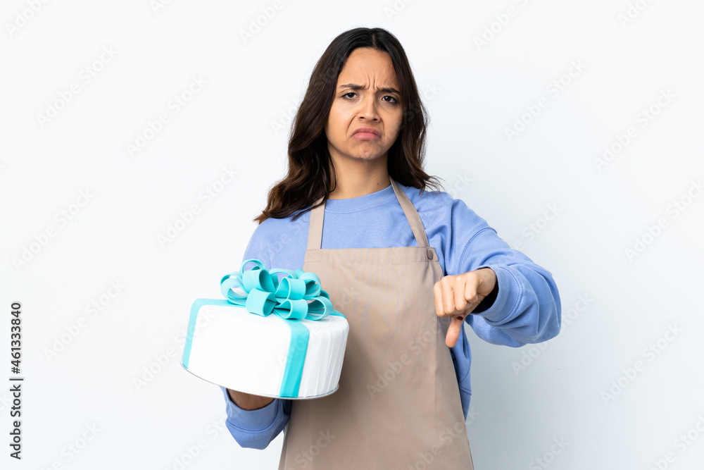Pastry chef holding a big cake over isolated white background showing thumb down with two hands Pastry chef holding a big cake over isolated white background showing thumb down with two hands