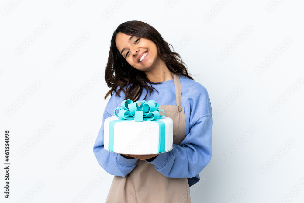 Pastry chef holding a big cake over isolated white background keeps palm together. Person asks for something