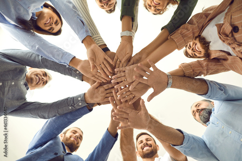 Human support. Bottom view of a group of different people standing in a circle and folding their arms together as a symbol of cooperation. Friends or business partners demonstrate unity and teamwork.